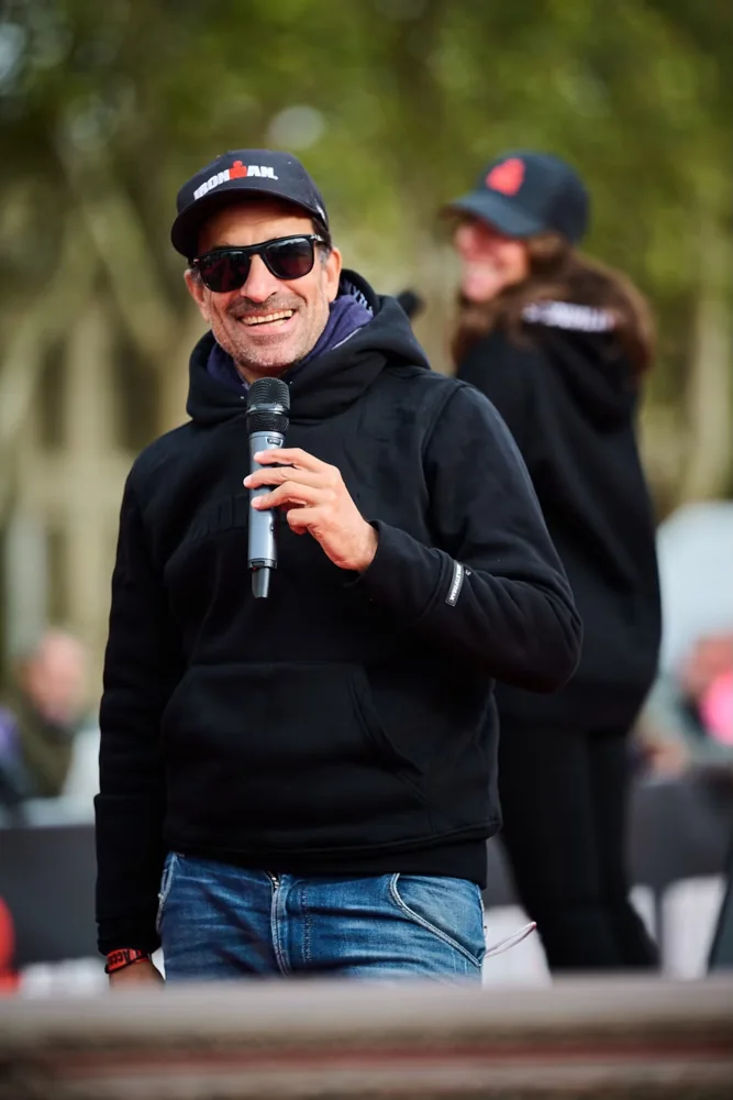 Julien Huët souriant, micro en main à l’IRONMAN 70.3 Versailles